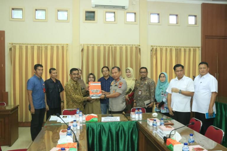 Ketua Bawaslu Sumbar Surya Efitimen serahkan buku Indeks Kerawanan Pemilu (IKP) kepada Kapolda Sumbar Irjen Pol Toni Harmanto, Kamis (12/3).(Foto : Istimewa)