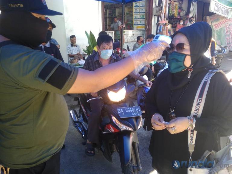 Petugas Pasar Tanah Kongsi, Kota Padang memeriksa suhu tubuh warga yang akan berbelanja di pasar tersebut, Senin (4/5).(Foto : dyz)