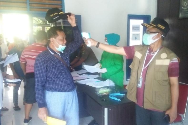 Koordinator Satgas Covid Matra Laut Sumbar, Yosmeri memeriksa suhu tubuh salah seorang penumpang KMP Ambu-Ambu yang akan berangkat ke Tuapejat, Mentawai, Minggu (31/5). (Dok : Istimewa)