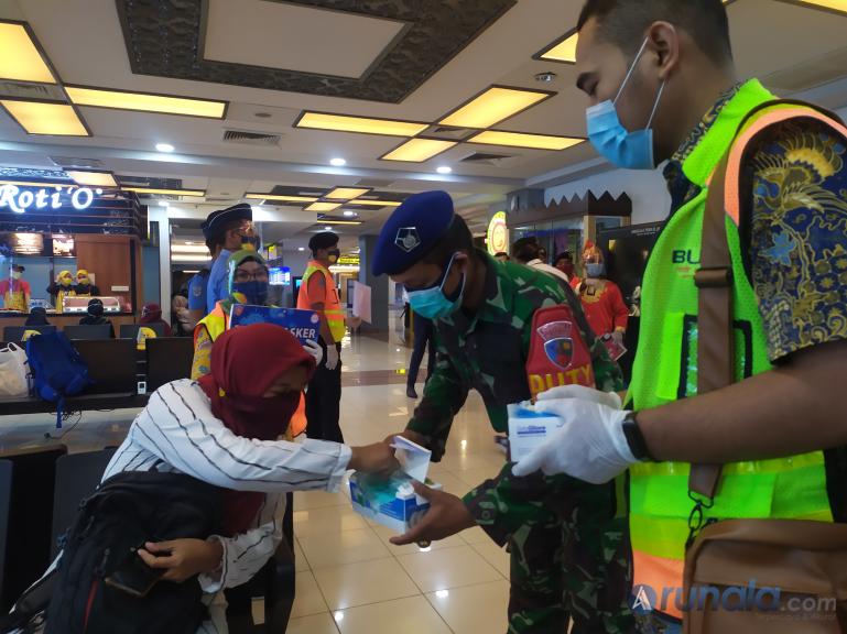 Petugas Bandara BIM dan petugas keamanan membagikan masker dan sarung tangan kepada calon penumpang pesawat di BIM, Jumat (18/9). (Foto : Amz)