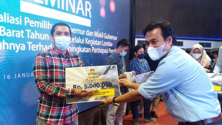 Pengamat Politik Unand Asrinaldi saat menyerahkan penghargaan kepada salah seorang jurnalis yang jadi pemenang utama untuk lomba penulisan artikel yang diadakan KPU Sumbar, Sabtu (16/1). (Dok : Istimewa)