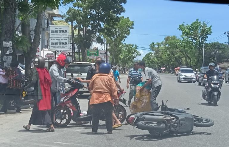 Warga berusaha memindahkan dua motor yang alami kecelakaan di Jalan S Parman Padang, Rabu siang (16/3). (Foto : Arzil)