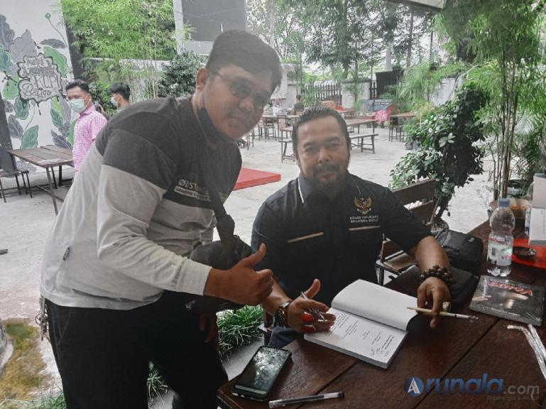 Komisioner KI Sumbar, Adrian Tuswandi membubuhkan tanda tangannya pada buku karyanya untuk salah seorang wartawan, Rabu (26/1). (Foto : Arzil)