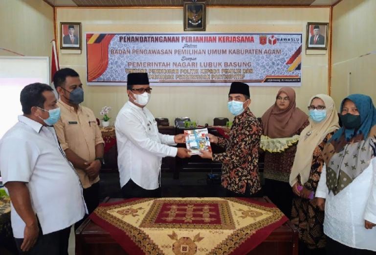 Ketua Bawaslu Agam, Elvys bersama Kasi Windra Purnama sesuai lakukan penandatanganan kerjasama pojok pengawasan Perpustakaan Bahrul Ulum Nagari Lubuk Basung, Jumat (25/2). (Dok : Istimewa)