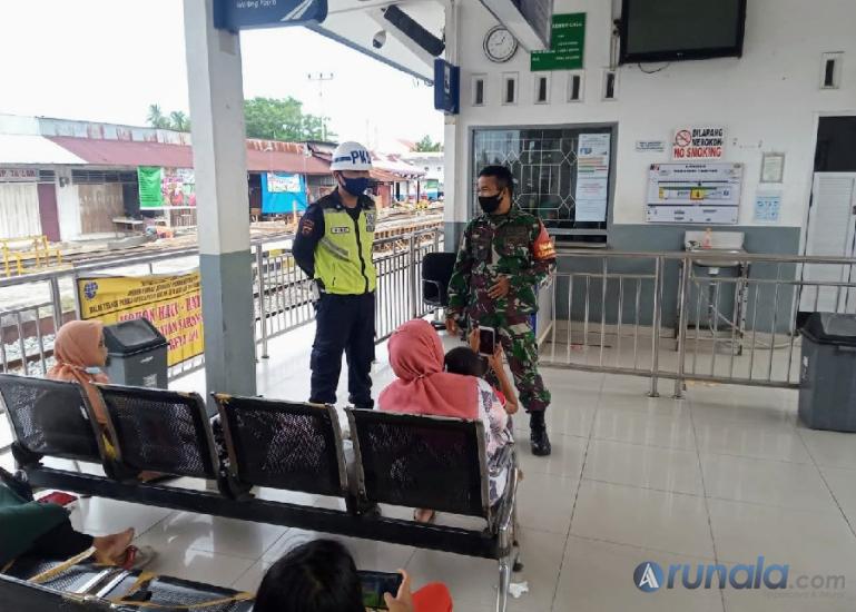 Babinsa Kelurahan Bungo Pasang, Serka Hendrianto bersama petugas keamanan PT KAI berikan prokes pada calon penumpang kereta api di Stasiun Tabing, kemarin siang. (Foto : Derizon)