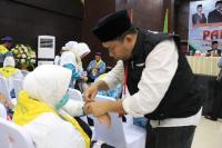 Petugas Penyelenggara Ibadah Haji (PPIH) Embarkasi Padang memasangkan gelang identitas dan memberikan nomor manifes kepada salah seorang CJH asal Padang di Aula Makkatul Mukarramah Asrama Haji, Senin (6/6). (Dok : Istimewa)