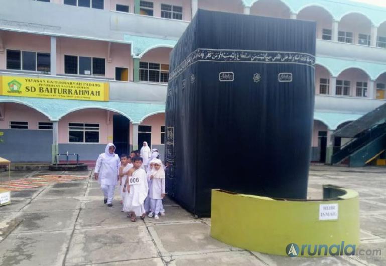 Murid kelas II SD Baiturrahmah didampingi guru kelas melaksanakan tawaf mengelilingi miniatur Kakbah saat Lomba Manasik Haji, di halaman sekolah, Kamis (28/7). (Foto : Fajril)