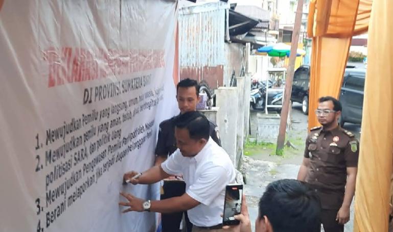 Anggota Bawaslu Sumbar, Muhammad Khadafi bubuhkan tanda tangan pada spanduk deklarasi pendirian Kampung Pengawas Pemilu di Kota Payakumbuh, Selasa (13/12). (Dok : Istimewa)