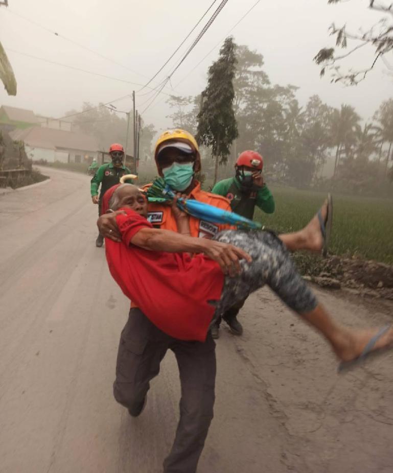 Seorang petugas BPBD sedang mengendong warga dalam upaya evakuasi akibat meletusnya Gunungapi Semeru, Minggu siang (4/12). (Dok : Istimewa)