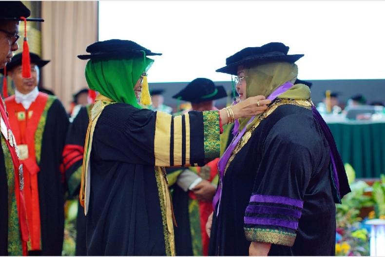 Ketua Dewan Profesor Unand Prof Dr Marlina MS Apt didampingi Rektor Unand Prof Dr Yuliandri SH MH mengalungkan tanda kehormatan profesor kepada Guru Besar Bidang Biologi Oral FKG Unand Prof Dr drg Nila Kasuma MBiomed di Convention Hall Unand, Selasa (22/8