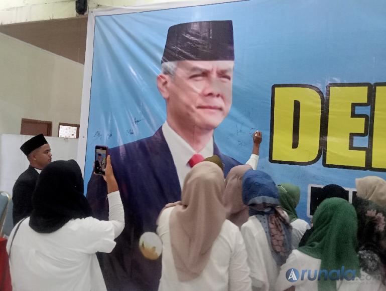 Ketua Milenial Sumbar Basamo Ganjar, Mahmuddin menyaksikan peserta membubuhkan tanda tangan di baliho deklarasi sebagai bentuk dukungan mereka pada Ganjar Pranowo, Minggu (17/9). (Foto : Arzil)