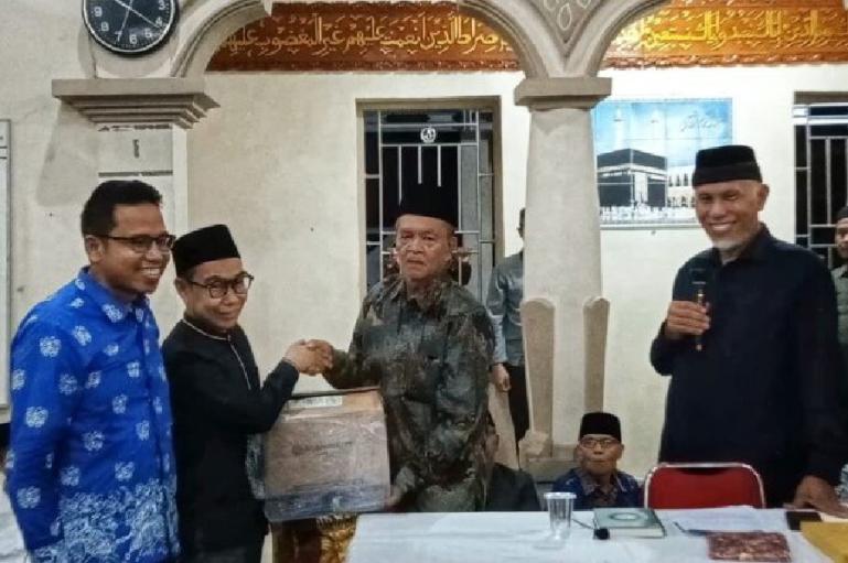 Ketua Komisi Informasi (KI) Sumbar, Musfi Yendra disaksikan Gubernur Mahyeldi serahkan sejumlah Al Quran kepada pengurus Masjid Raya Lubuk Pandan, Padangpariaman, Selasa malam (19/3). (Dok : Istimewa)