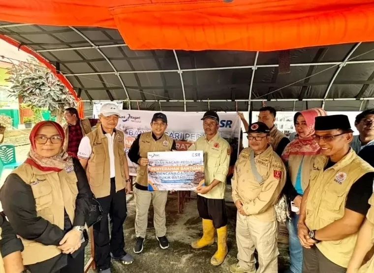 Pjs Direktur Utama Bank Nagari Gusti Candra saat menyerahkan paket bantuan sembako untuk korban banjir lahar dingin di Posko Penanggulangan Bencana Bukit Batabuah, Senin (8/4/2024). IST