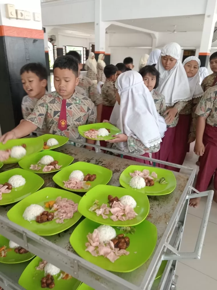 Murid SD Baiturrahmah antre mengambil makan siang yang telah disajikan di aula sekolah. Dok SD Baiturrahmah