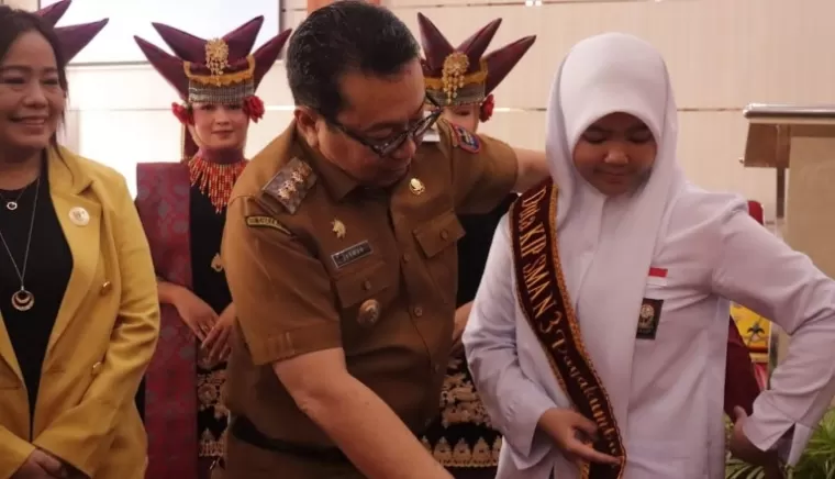 Komisioner KI Pusat, Rospita Vici Paulyn, saksikan Pj Wali Kota Payakumbuh, Jasman Rizal pasangkan selempang Duta KIP kepada salah satu siswa SMA saat peringatan Hakin 2024 di Sumbar, Selasa (30/4/2024). (Dok : KI Sumbar)