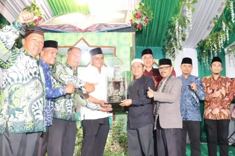 Kepala BKPSDM Kota Padang, Mairizon serahkan piala juara umum lomba MTQ se Kecamatan Lubeg, Selasa (11/6/2024) malam. (dok : istimewa)