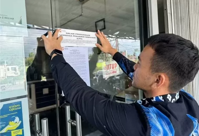 Pemasangan stiker dalam penguasaan Lembaga Penjamin Simpanan di pintu PT BPR Lubuk Raya Mandiri. IST