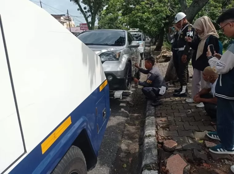Petugas Dishub Kota Padang menderek mobil yang parkir sembarangan di kawasan Jalan Perintis Kemerdekaan Jati, Selasa (20/8/2024). Diskominfo Kota Padang