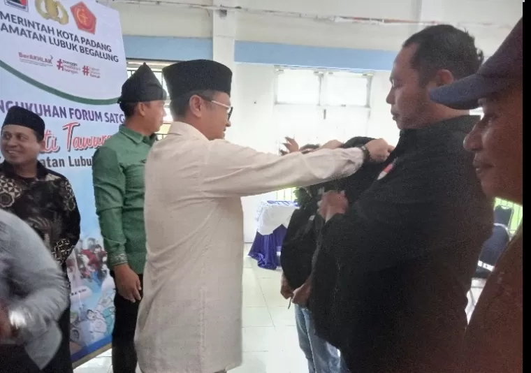 Kepala Dinas Dikbud Kota Padang, Yopi Krislova dan Camat Lubeg Andi Amir memasangkan rompi kepada anggota forum anti tawuran se Kecamatan Lubeg, Jumat (4/10/2024). (dok : arunala.com)