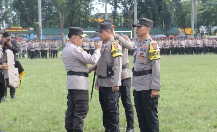 Kapolda Sumbar, Irjen Pol Suharyono memasangkan pita tanda pengamanan pilkada pada perwakilan Bhabinkamtibmas, saat apel pasukan di Lapangan Imam Bonjol Padang, Kamis (17/10/2024). (dok : arunala.com)