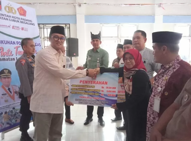 Kadisdikbud Kota Padang, Yopi Krislova didampingi Camat Lubeg, Andi Amir serahkan bantuan dana operasional kepada RT/RW di kecamatan itu, Jumat (4/10/2024). (dok : arunala.com)