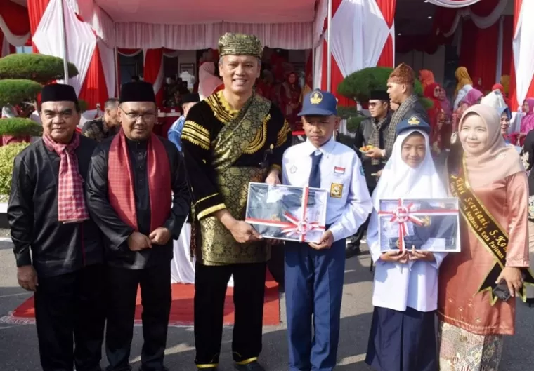 Pj Wali Kota Pariaman Roberia didampingi Pimpinan Cabang Bank Nagari Pariaman, Ibnu Supriadi, serahkan bantuan seragam sekolah pada siswa kurang mampu, Minggu (29/9/2025). (dok : istimewa)