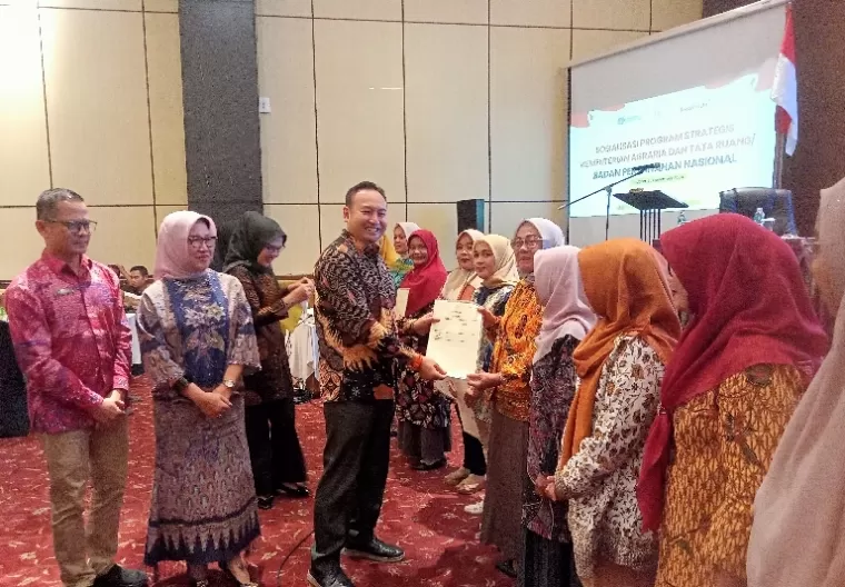 Anggota Komisi II DPR RI, Rahmat Saleh didampingi kepala Kanwil ATR/BPN Sumbar, Sri Puspita Dewi secara simbolis serahkan sertifikat tanah program PTSL kepada 10 masyarakat di Padang, Sabtu (30/11/2024). (dok : arunala.com)