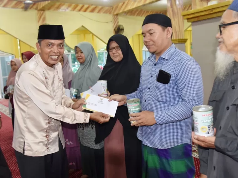 Ketua Baznas Kota Pariaman Zalman Zaunit salurkan kepada salah seorang guru MDTA, Senin (23/12/2024). IST