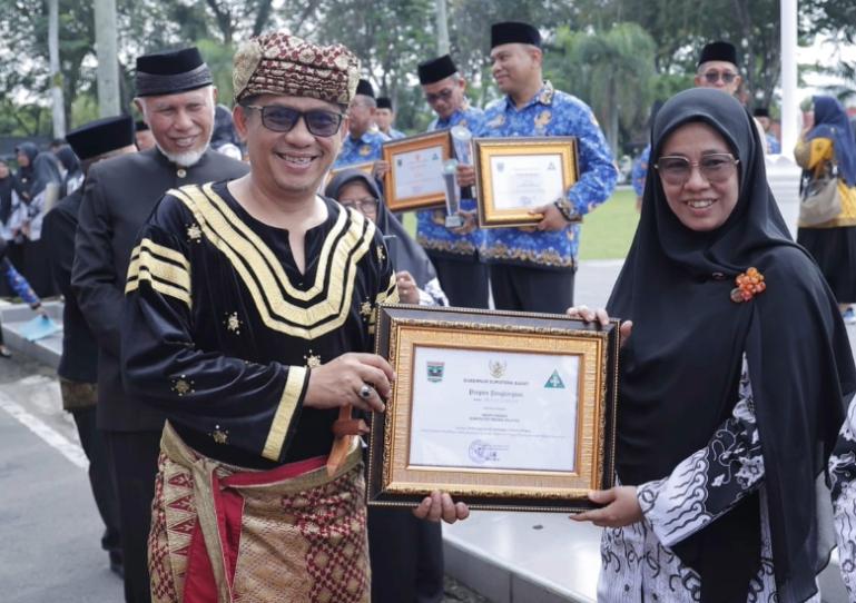Wakil Ketua DPRD Sumbar, Evi Yandri serahkan perhargaan pada seorang tenaga pendidikan saat peringati Hari Pendidikan Nasional di halaman Kantor Gubernur Sumbar, Jumat (2/5/2025).  (dok : humas dprd sumbar)
