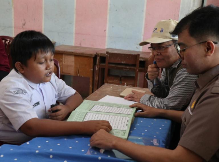 Kepala Badan Bahasa Hafidz Muksin menyaksikan salah satu calon siswa SMP N 26 Kayu Kalek Kota Padang diuji kemampuan baca Al Quran oleh guru penguji di SMP itu, Kamis  (26/6/2025). IST