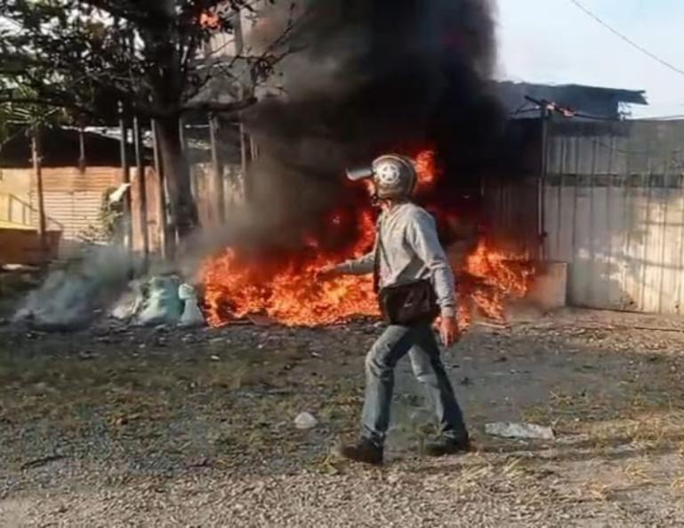 Seorang warga melintas dekat kobaran api yang membakar Gudang pengumpul barang bekas di Jalan Bypass KM 13 (Simpang RSUD Padang), Selasa pagi (27/1/2026). IST