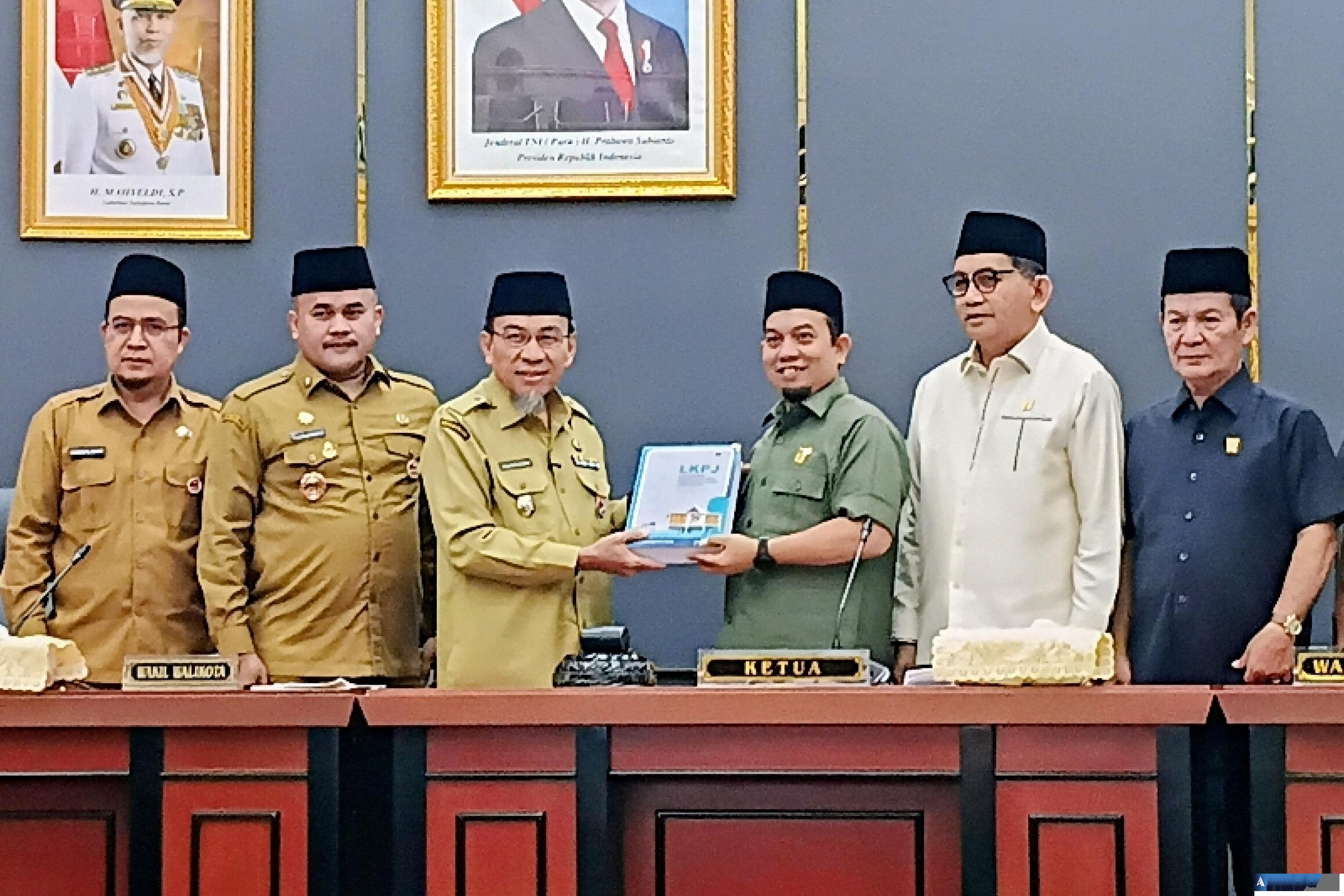 Ketua DPRD Kota Padang Muharlion disaksikan para wakil ketua menerima dokumen penjelasan dari LKPJ Wali Kota 2025 yang diserahkan Wakil Wali Kota Maigus Nasir dalam rapat paripurna, Senin siang (9/3/2026). (dok : arunala.com)