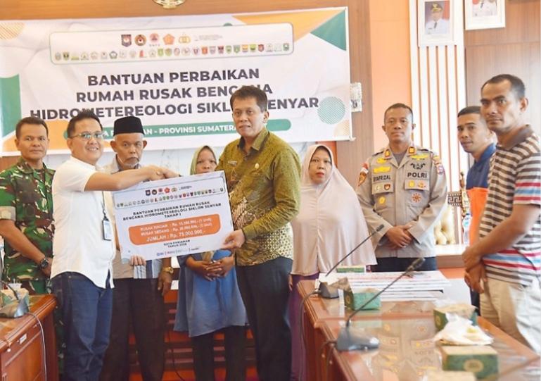 Asisten I Setko Pariaman Elfis Candra, secara simbolis terima bantuan rehab rumah terdapak bencana dari pemerintah pusat melalui pimpinan BRI Cabang Pariaman, Jumat (13/2/2026). IST