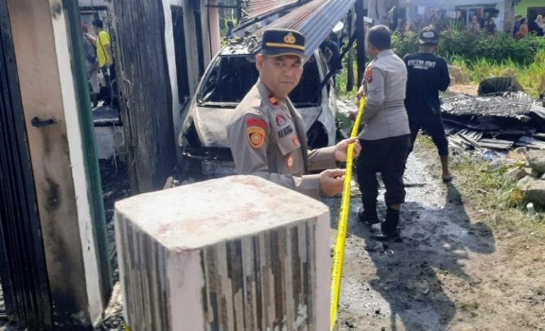 Petugas kepolisian memasang garis polisi di lokasi bekas kebakaran di Palupuh, Agam, yang terjadi kemarin. IST