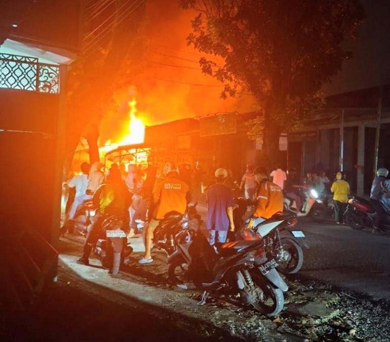 Warga menyaksikan kobaran api membara yang menghaguskan depot air minum isi ulang dan satu rumah di Jalan Lolon Karan, Sungai Sapih, Kuranji, Selasa malam (13/10/2026). IST
