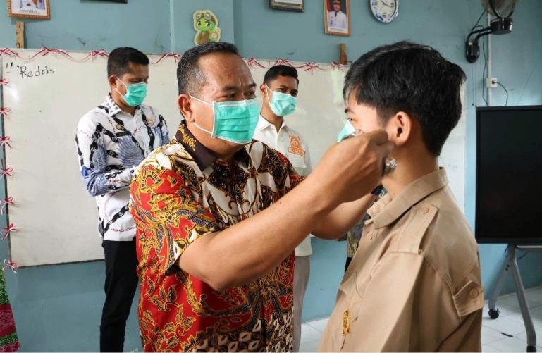 Seorang siswa di Kota Pariaman sedang dipasangkan masker oleh Wali Kota Yota Balad. Langkah ini untuk pencegahan kabut asap yang kian menebal di kota itu, Kamis (10/9/2026).